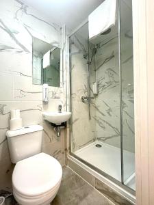 Un baño con inodoro, lavabo y ducha. en Kings Cross Hotel London, en Londres 71 fotos más