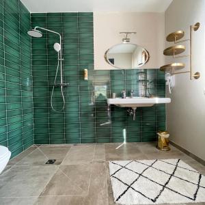 een badkamer met een wastafel en een douche met groene tegels bij CASA VOLTEGIRA in Manso