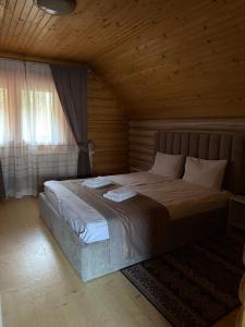 a bedroom with a large bed in a wooden room at Котедж "Villa Затишна" in Mykulychyn