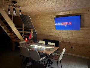 a dining room with a table with chairs and a tv at Joy Chalet in Plaiu