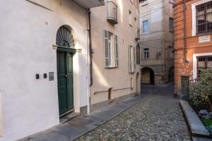 an alley with a green door on a building at Casa Piazzetta in Saluzzo