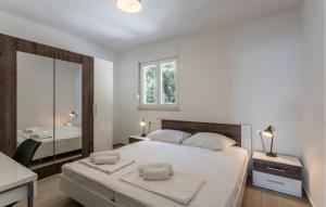 a white bedroom with a large bed and a mirror at Beautiful Apartment In Dingac With Swimming Pool in Gornji Dingač