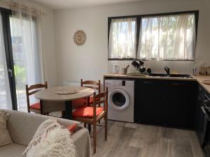 a kitchen with a washing machine and a table at Maisonnette Hauts d'Evian in Larringes
