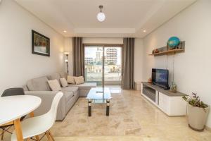 a living room with a couch and a tv and a table at plénitude in Mohammedia