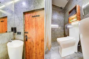 a bathroom with a toilet and a wooden door at Collection O Baga Beach Goa Formerly Traveller Guest House in Baga