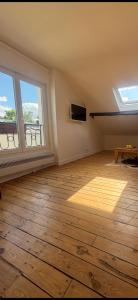an empty living room with windows and a wooden floor at Logement atypique in Asnières-sur-Seine