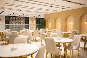 a dining room with tables and chairs and windows at HDN Hotel فندق هدن in Mecca