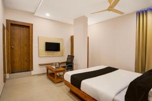 a bedroom with a bed and a chair and a television at Hotel O The Classic Crown in Jālahalli