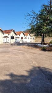 eine Reihe weißer Häuser mit einem Baum und einer Straße in der Unterkunft Pousada Gaturama suite 1 in Corumbá