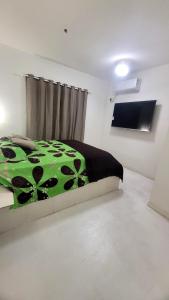 ein Schlafzimmer mit einer grünen Bettdecke in der Unterkunft Pousada Gaturama suite 1 in Corumbá