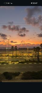 um pôr do sol sobre uma rua com palmeiras e uma estrada em SeaSide Villa em Asdode