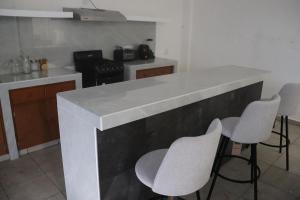 een keuken met een aanrecht en 2 krukken bij Habitacion con baño privado La Perla in Acapulco +4 foto's