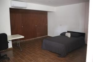 een slaapkamer met een bed, een bureau en een tafel bij Habitacion con baño privado La Perla in Acapulco