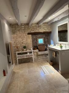 Domaine de pierre blanche في Pern: حمام مع حوض وجدار حجري