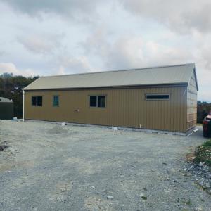 a large yellow building with a metal roof at Winder-Lea Whare in Native Bush in Moana