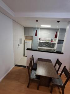Una cocina con mesa y sillas y un refrigerador. en Family Flat PG - Praia, Musica e Gastronomia, en Praia Grande