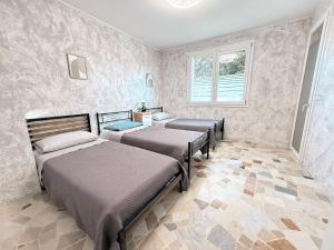 a bedroom with three beds and a window at Casa Buda 2BR Apartment-Lakes Malpensa MXP 24h Check-in Parking in Sesto Calende +12 photos