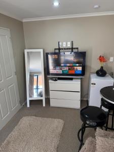 Una sala de estar con un televisor de pantalla plana sobre una cómoda. en Casa Miguelle a Private mini house, en Dunedin