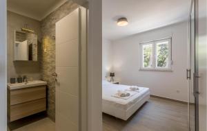 a white bathroom with a bed and a sink at Cozy Apartment In Dingac With House Sea View in Gornji Dingač