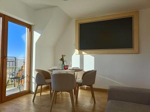 een woonkamer met een tafel met stoelen en een flatscreen-tv bij Apartament 7niebo in Gliczarów Górny