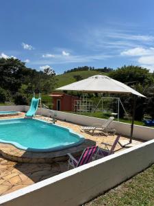 エストレーマにあるSítio do Beto Extrema MGの椅子2脚と傘が備わったプール