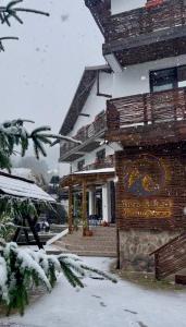 a building with a sign on it in the snow at Pensiunea Bike&Bed in Moieciu de Jos