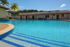 a large swimming pool with blue water in front of a building at Sea Breeze Villa in Fajardo