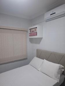 a bedroom with a white bed and a window at Casa 2 Encanto dos Mares in Itapema