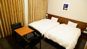 a hotel room with two beds and a wooden table at Dormy Inn Kanazawa Natural Hot Spring in Kanazawa