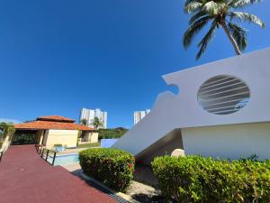 a white building with a palm tree in the background at Sea Breeze Villa in Fajardo