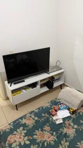 een flatscreen-tv zittend op een wit entertainment center bij 1 double bed, 1 single bed, bathroom and kitchen in Botucatu