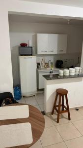 een keuken met een aanrecht, een koelkast en een kruk bij 1 double bed, 1 single bed, bathroom and kitchen in Botucatu