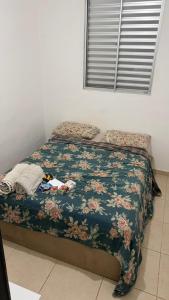 een slaapkamer met een bed met een bloemdekbed bij 1 double bed, 1 single bed, bathroom and kitchen in Botucatu