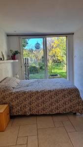 een slaapkamer met een bed en een groot raam bij La suite d'Ananda in Villefranche-de-Rouergue