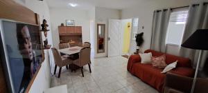 Espaço do acalanto- Quarto em apartamento compartilhado في ناتال: غرفة معيشة مع أريكة وغرفة طعام