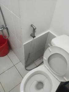 a white toilet in a bathroom with a red bucket at Nicecondotel in Manila