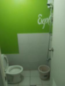 a bathroom with a toilet and a green wall at Nicecondotel in Manila