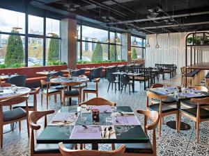 un restaurante con mesas, sillas y ventanas en ibis Styles Sarajevo, en Sarajevo