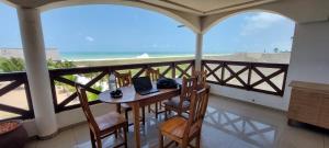 Grand-PopoGuesthouse Bambou Beach的阳台配有桌椅,享有海景。
