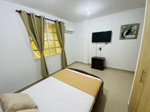 a small bedroom with a bed and a television at Hotel Piedra Mágica in Capurganá