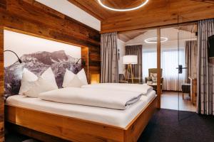 a bedroom with a large bed with white pillows at Hotel Jagdhof in Riezlern