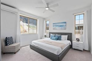 a bedroom with a bed and a chair and windows at Marbella Lane - Elegant 3BR w Marvelous Views in Waianae