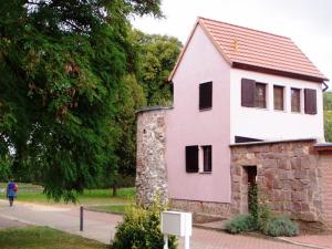 una piccola casa rosa con una persona che ci passa davanti di Ferienhaus Kyffhäuser a Bad Frankenhausen/Kyffhäuser