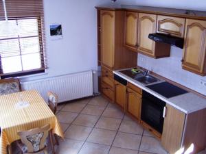 uma cozinha com armários de madeira, uma mesa e um lavatório em Ferienhaus Kyffhäuser em Bad Frankenhausen