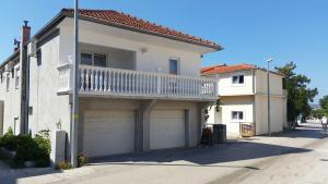 a white house with a balcony and a garage at Apartmani kod Rade in Pakoštane
