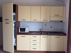 バデージにあるCasa Vacanze Residence I delfiniの白いキャビネット、シンク、電子レンジ付きのキッチンが備わります。