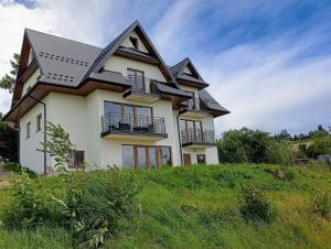 een huis bovenop een grasheuvel bij Apartament 7niebo in Gliczarów Górny