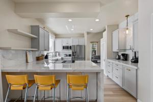 カポレイにあるMarbella Lane Posh 4BR with Spectacular Viewsのキッチン(白いキャビネット、黄色のバースツール付)
