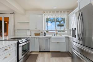 カポレイにあるMarbella Lane Posh 4BR with Spectacular Viewsの白いキャビネットとステンレス製の電化製品を備えたキッチン