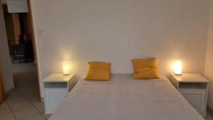 two yellow pillows on a bed with two lights on it at L'appartement d'Ananda in Villefranche-de-Rouergue